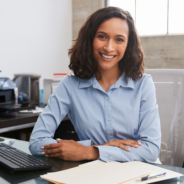 Young female professional at desk smiling to camera