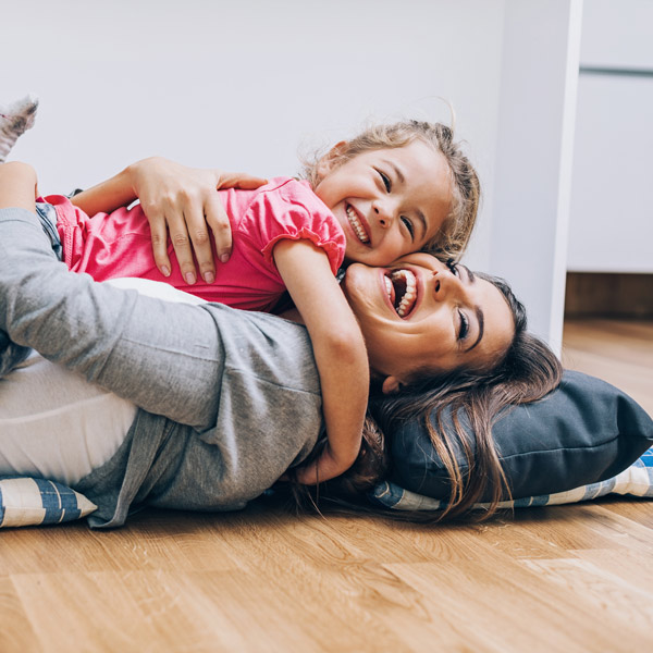 Happy mother and daughter playing and embracing on the floor